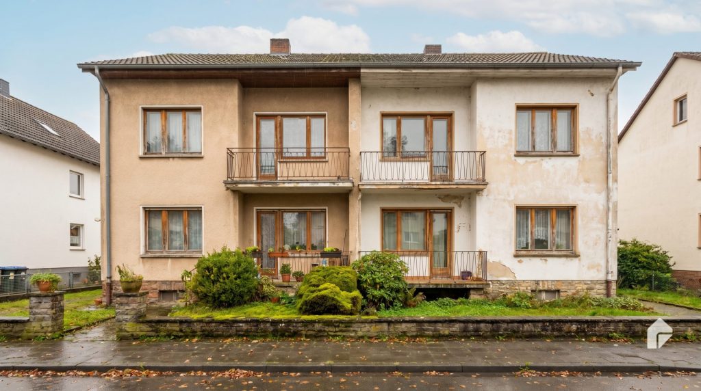 Das Motiv zeigt genau die Art von Bestandsimmobilie, um die es im Artikel geht: ein freistehendes, älteres Mehrfamilienhaus mit sichtbar gealtertem Zustand. Dadurch wirkt das Bild glaubwürdig, sachlich und relevant für das Thema Verkauf einer solchen Immobilie sowie die strategische Auseinandersetzung mit deren wirtschaftlichen und steuerlichen Aspekten.
